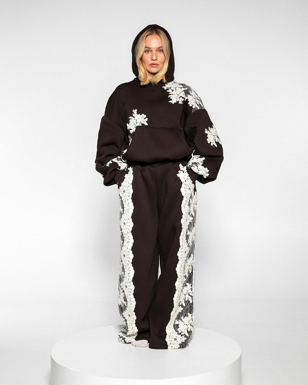 Model wearing a dark brown tracksuit with white lace, full length